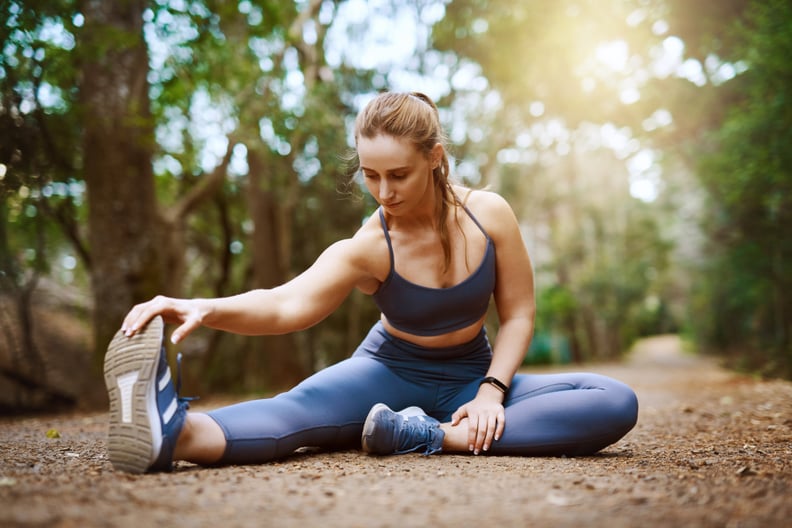 Shot of a sporty young woman stretching her legs while exercising outdoors