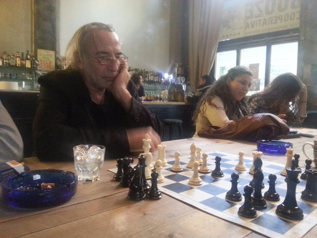 This picture shows a scene that's common in Greece: men playing chess in a coffee shop.