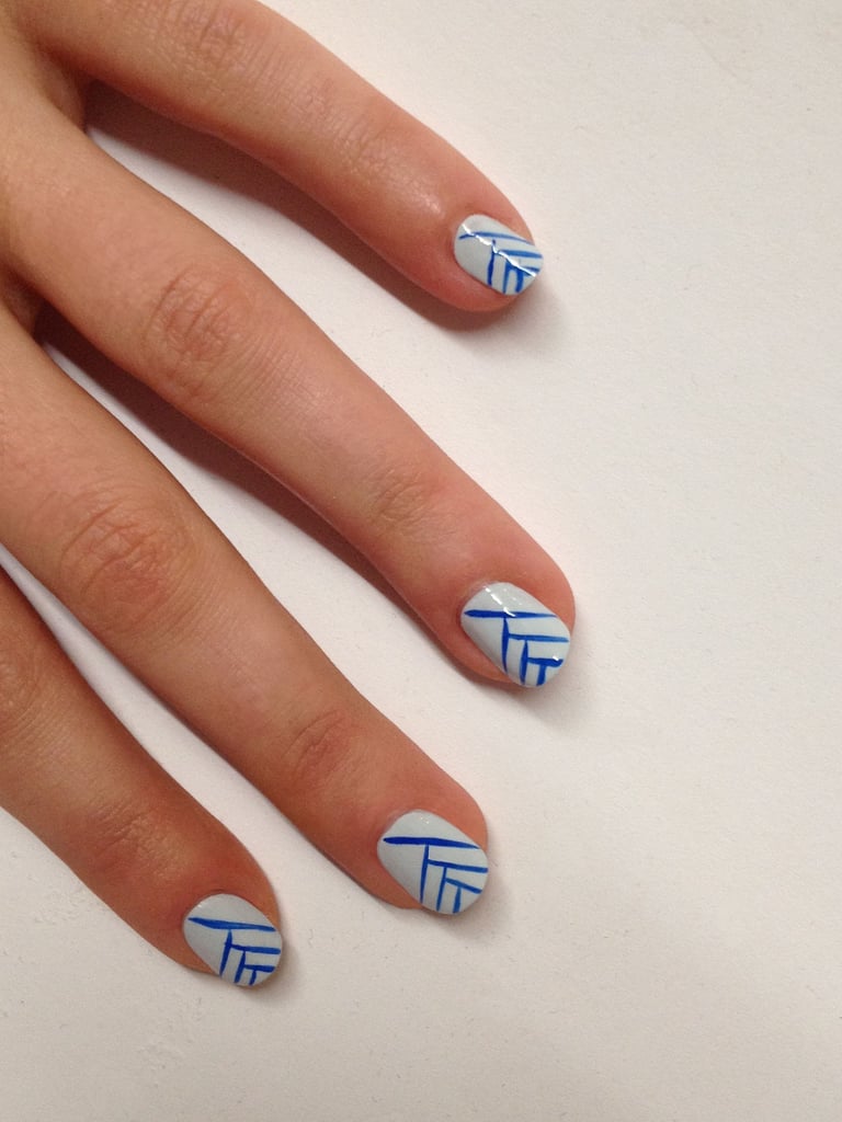 File and shape your nails to a natural square shape.
Apply a base coat like JINsoon Power Coat ($18).
Apply two coats of JINsoon Kookie White ($18) on the entire nail bed.
With a thin brush, create thin lines using JINsoon Cool Blue ($18). Paint the first line from the top of the nail at a diagonal, ending at the opposite side of the nail. Then paint the second line perpendicular to the first line about a third of the way down the nail. Continue painting at right angles from the previous line (as shown in the photo) until you reach the end of the nail.
Apply a top coat like JINsoon Top Gloss ($18) for a lasting glossy finish.