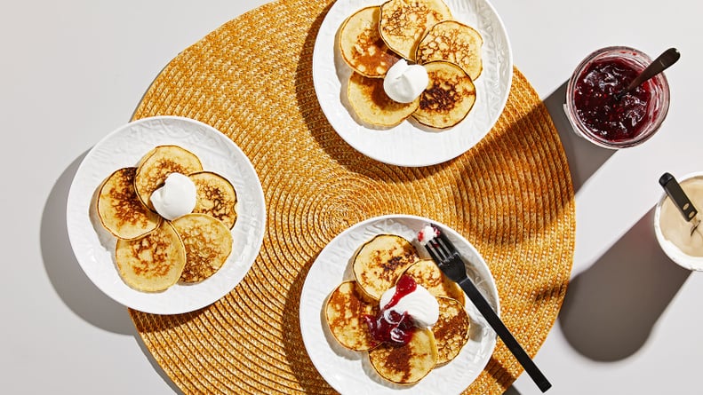 three plates of ricotta pancakes with jam and cream