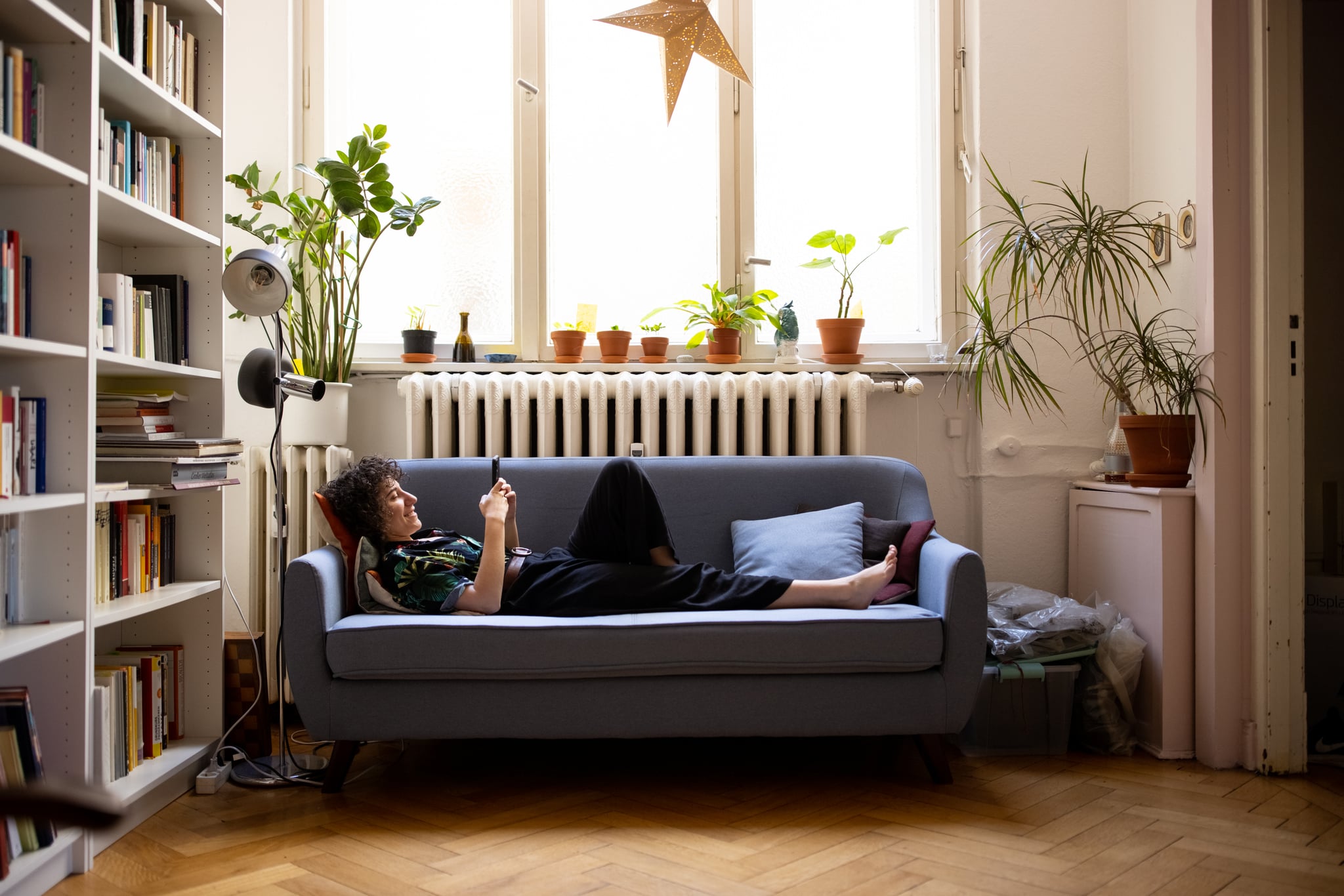 Nonbinary person texting on the couch