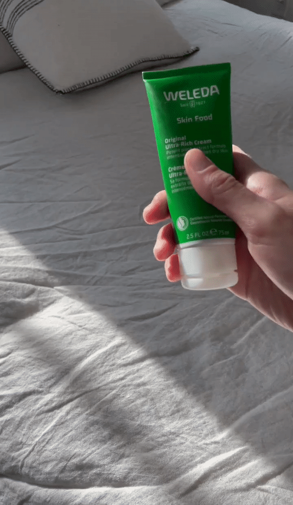 Woman rubbing Weleda Skin Food's Original Ultra-Rich Cream into her hands.