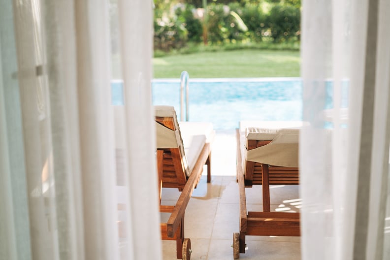 The view from hotel room through the curtains to sun beds and pool
