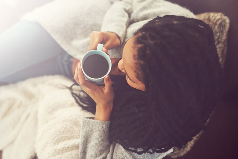 Shot of a young woman enjoying a cup of coffee at home
