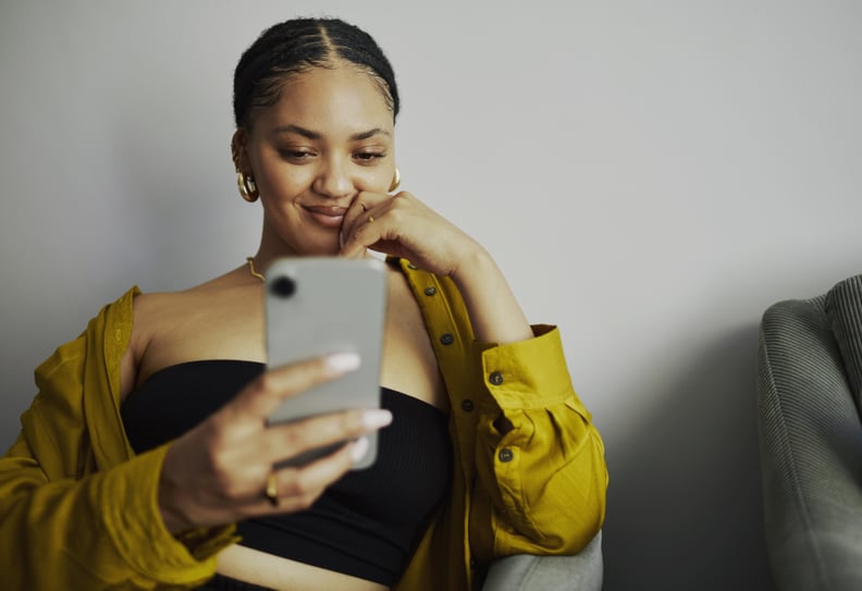 Young Woman Sitting Looks at Phone