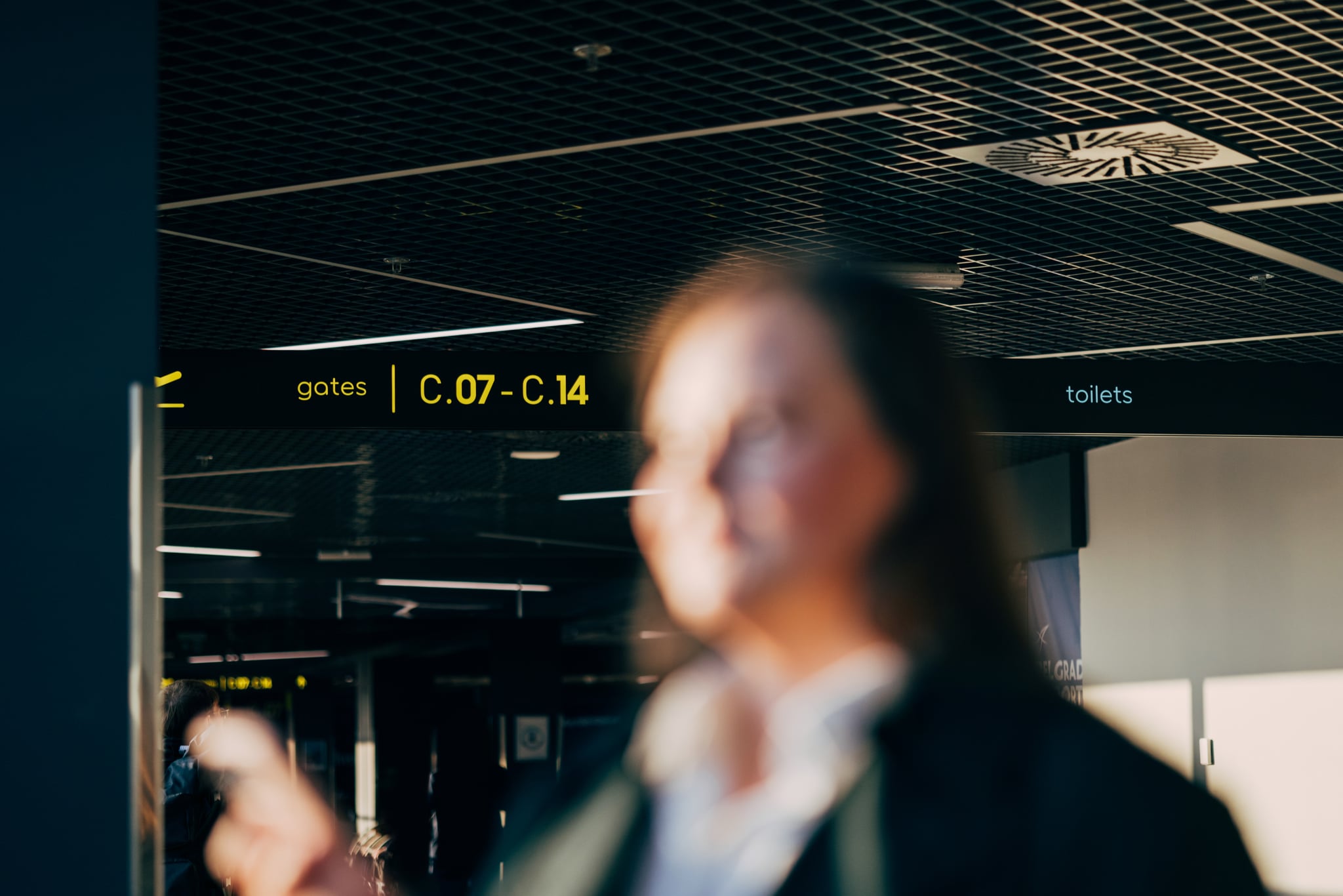 A blurred image of a plus-size traveler with airport terminals and gate signs in the background.