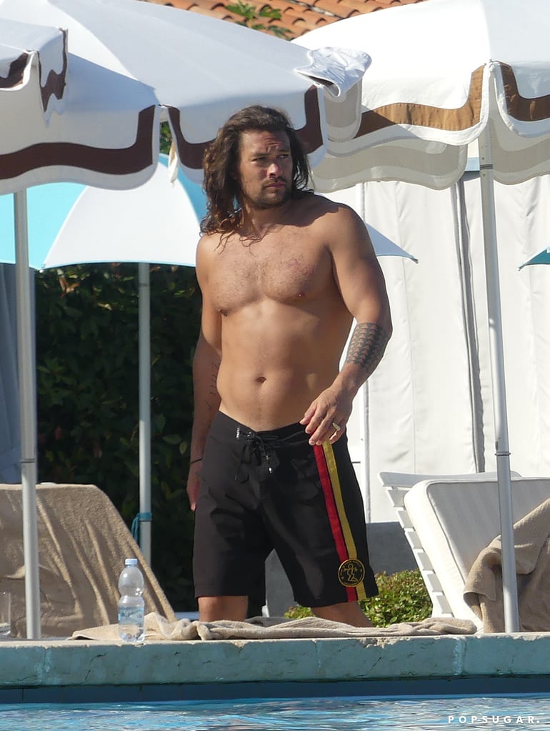 Jason Momoa and Lisa Bonet are bringing the heat to Venice. Shortly after Lisa's daughter, Zoë Kravitz, tied the knot with Karl Glusman in Paris, Jason and Lisa spent the afternoon poolside in Italy — the prime way to enjoy Summer, IMO. On Tuesday, Jason lounged shirtless by the water (peep the signature scruff growing back nicely) while Lisa strolled around wearing a beachy red dress and tan fedora. 
Jason and Lisa are taking their time in Europe with their children, 11-year-old Lola and 10-year-old Nakoa-Wolf, after celebrating Zoë's wedding weekend. The Aquaman actor and former Cosby Show star have been together since 2005 when they met through a mutual friend, and subsequently married in October 2017. They've been making PDA-heavy red carpet appearances ever since, and we love them for it. Ahead, see even more snaps from their temperature-raising getaway.