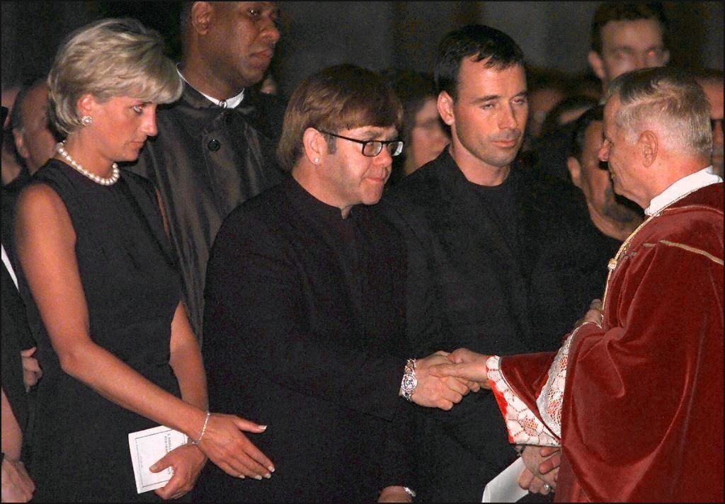 Archpriest Magio (R) shakes hands with British rock star Elton John standing next to Princess Diana (L) during the requiem mass for Italian fashion designer Gianni Versace at the Duomoin Milan 22 July 1997. Versace was gunned down in Miami Beach 15 July. EDS NOTE: Best quality available. (ELECTRONIC IMAGE) (Photo credit should read GERARD JULIEN/AFP/Getty Images)
