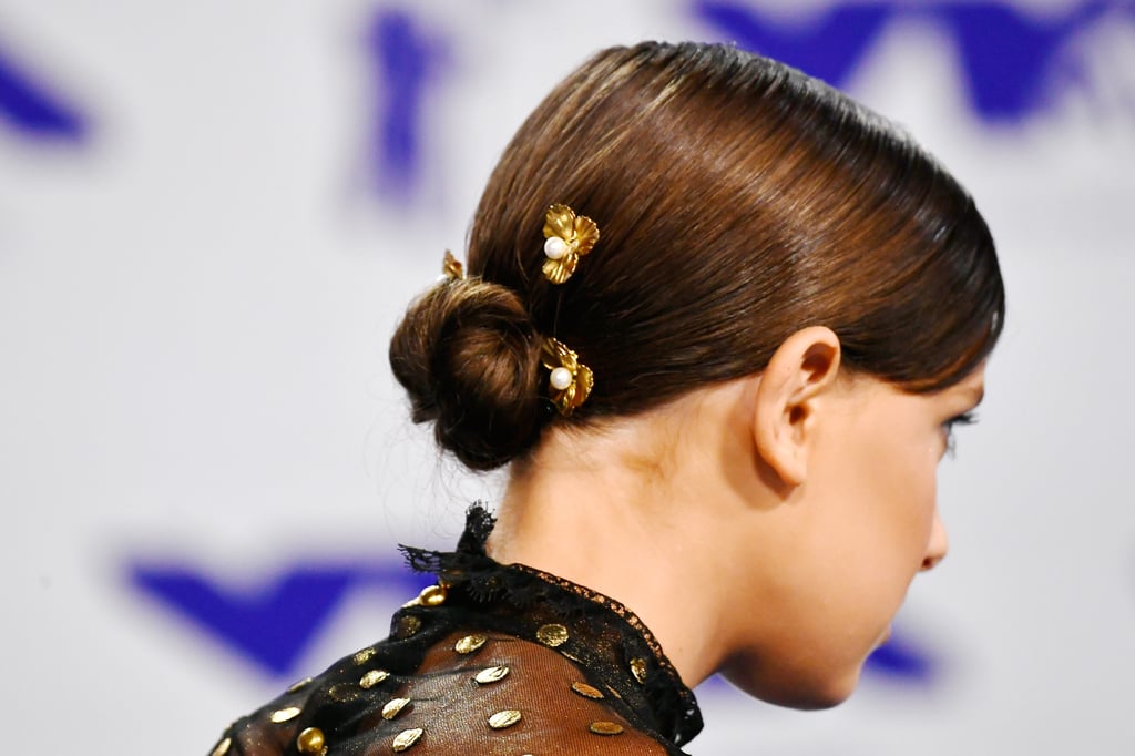 From the back, we can see that Millie's sleek, twisted bun is held up by gold-and-pearl hairpins.