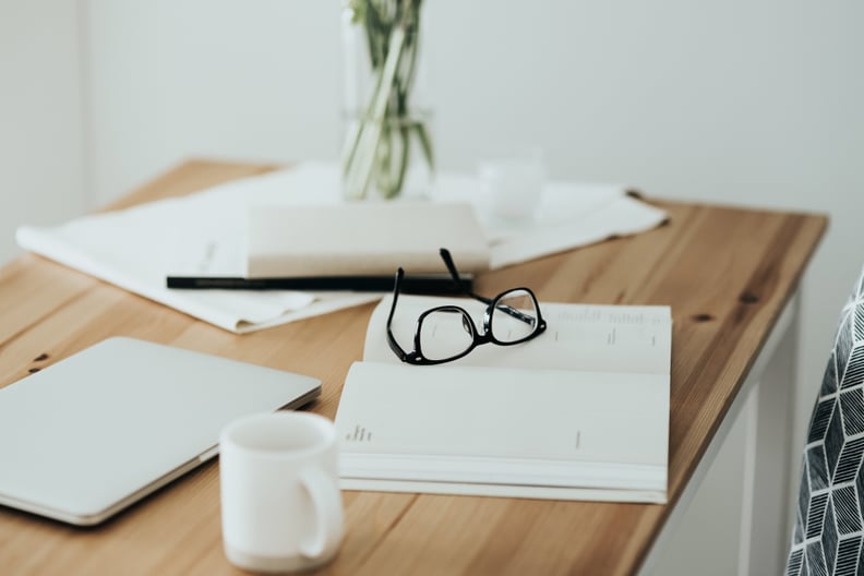 Workspace table with laptop, eyeglasses, schedule calendar and coffee