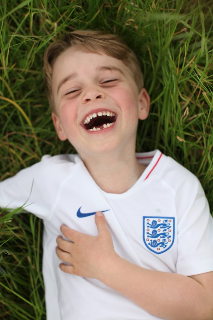 Prince George is turning six, and wow, he's growing up right before our eyes! The young royal is all smiles wearing an England national team jersey in his official portraits, which were released by Prince William and Kate Middleton the day before his July 22 birthday. 
"The Duke and Duchess of Cambridge are very pleased to share new photographs of Prince George to mark His Royal Highness's sixth birthday," the photos caption reads. "This photograph was taken recently in the garden of their home at Kensington Palace by The Duchess of Cambridge." 
It appears George must be a soccer fan (or a football fan, depending on where you're from) judging by his adorable attire. This love of sports runs in the family — William participated in a polo match earlier this month and Kate is prone to showing off her athletic abilities, as well. George has even taken tennis lessons from Roger Federer. Here's to another year full of royally fun activities!