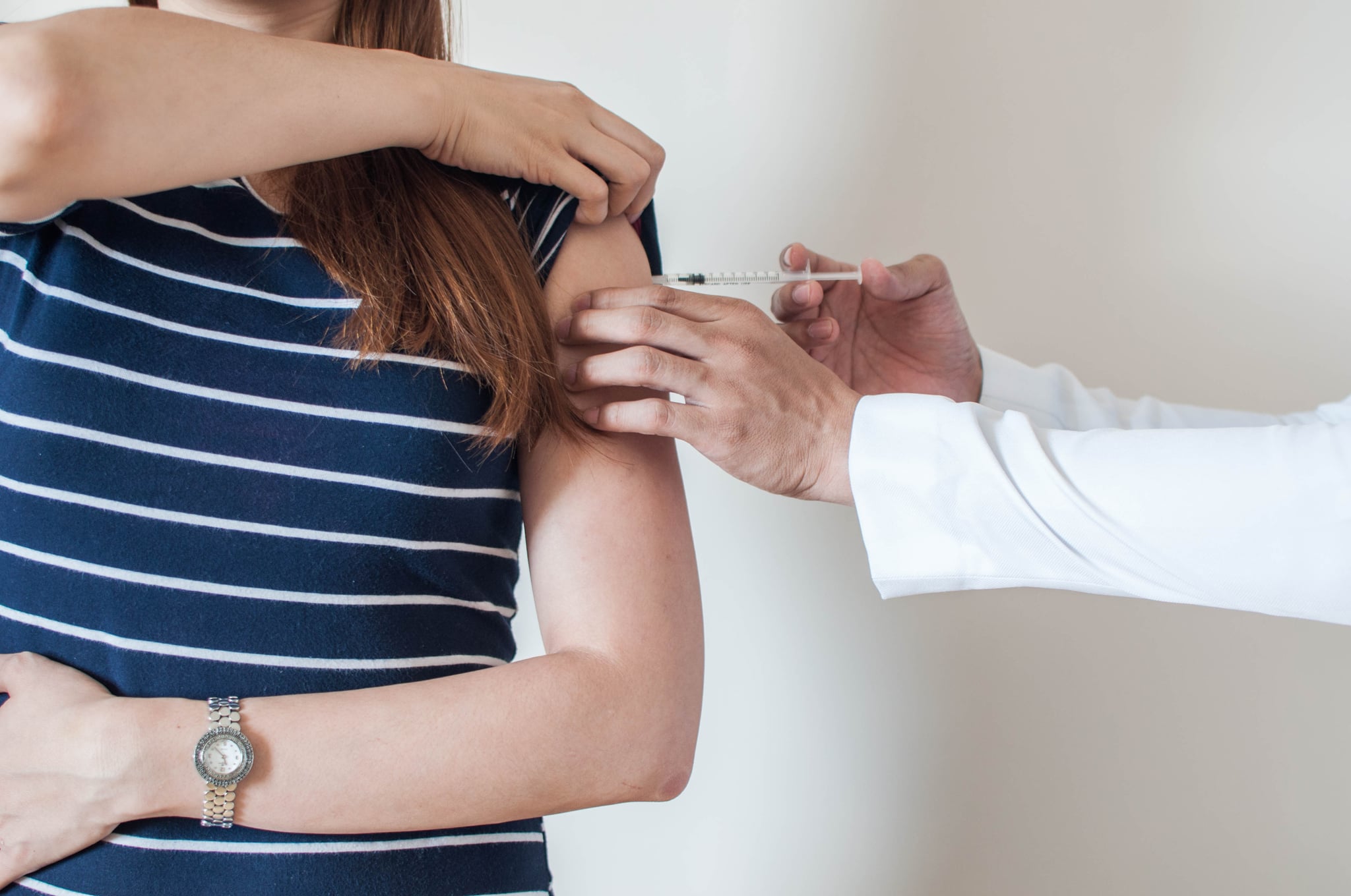 A doctor is giving a vaccine to a young woman on a white background