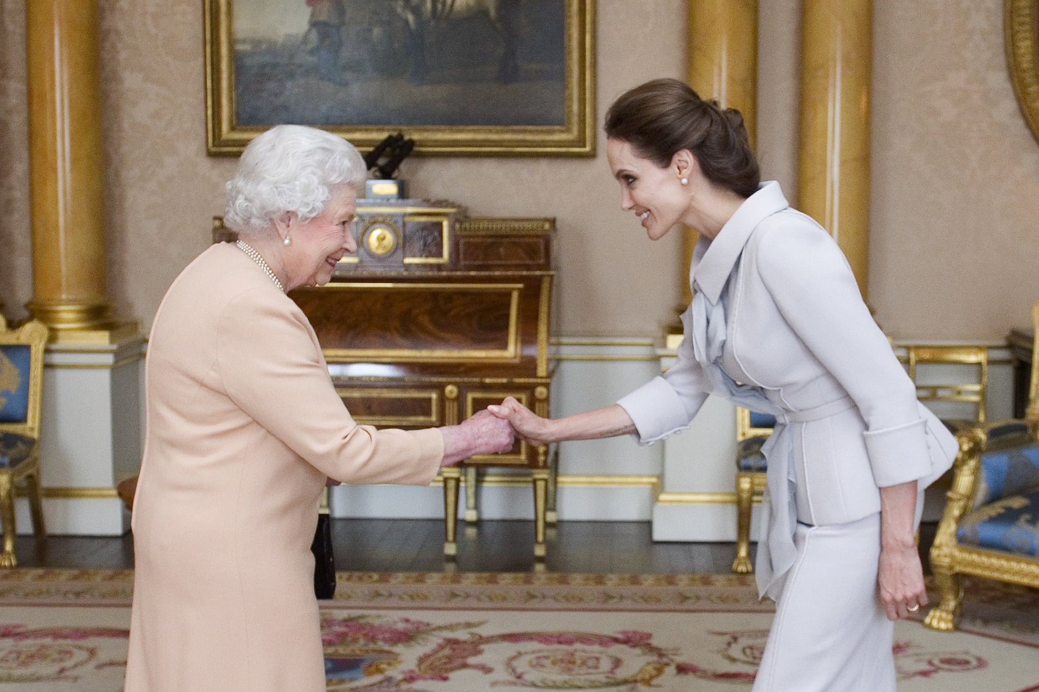 US actress Angelina Jolie (R) is presented with the Insignia of an honourary Dame Grand Cross of the Most Distinguished Order of St Michael and St George by Britain's Queen Elizabeth II in the 1844 Room at Buckingham Palace in central London, on October 10, 2014. Angelina Jolie was awarded an honourary damehood (DCMG) for services to UK foreign policy and the campaign to end war zone sexual violence. AFP PHOTO/Anthony Devlin/POOL        (Photo credit should read Anthony Devlin/AFP/Getty Images)