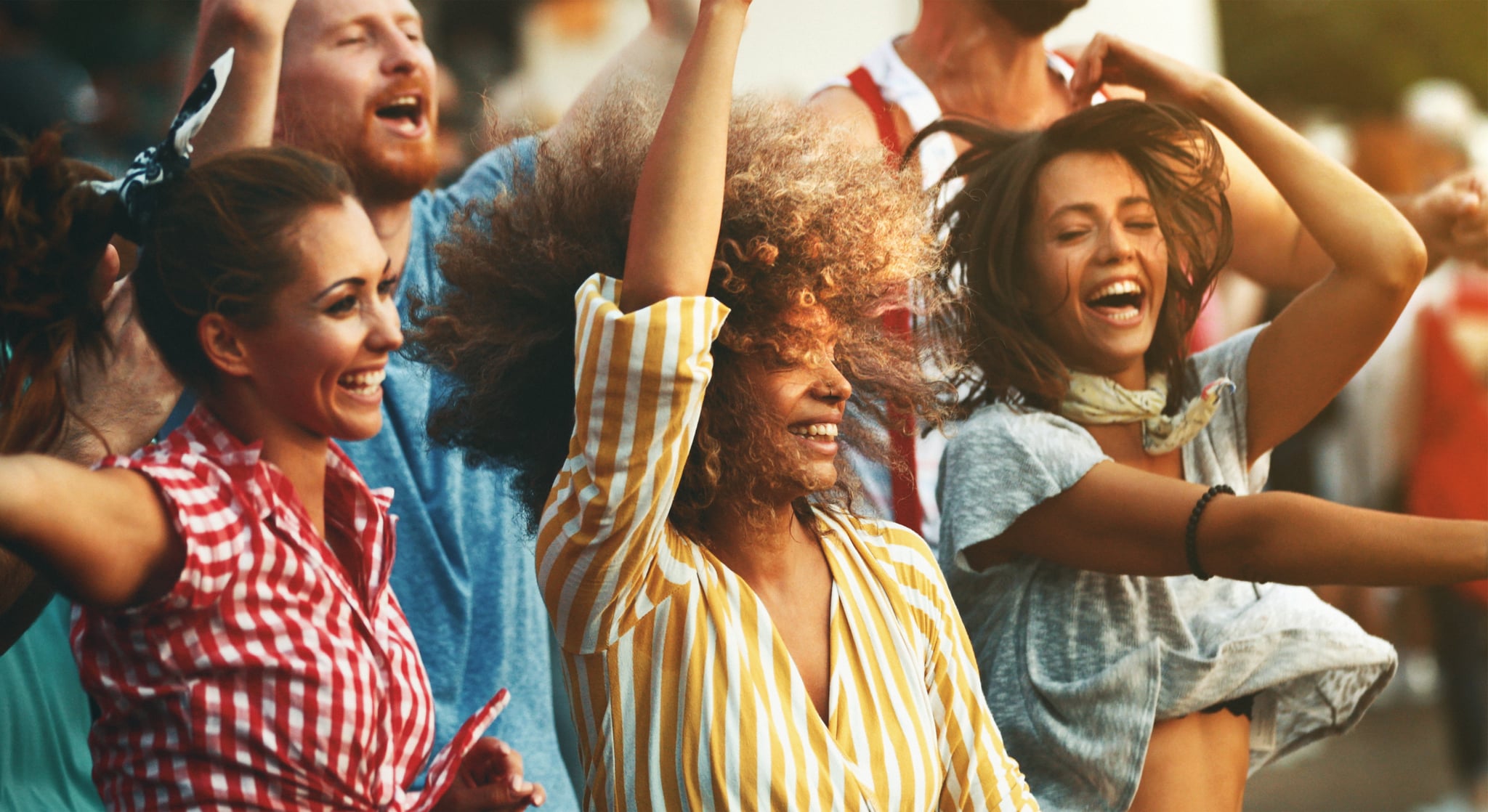 Closeup side view of group of group young adults having fun at a concert on a summer afternoon.