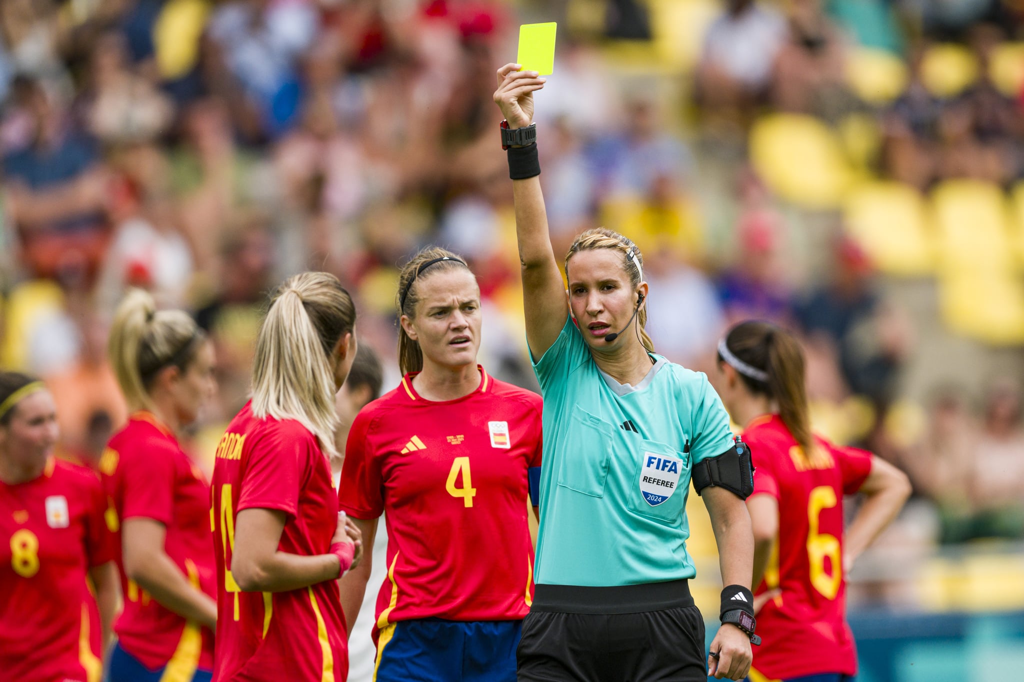 NANTES, FRANCE - JULY 25: Referee Bouchra Karboubi (R) shows a yellow card for Laia Aleixandri of Spain (L) during the Women's group C match between Spain and Japan during the Olympic Games Paris 2024 at Stade de la Beaujoire on July 25, 2024 in Nantes, France. (Photo by Marcio Machado/Eurasia Sport Images/Getty Images)
