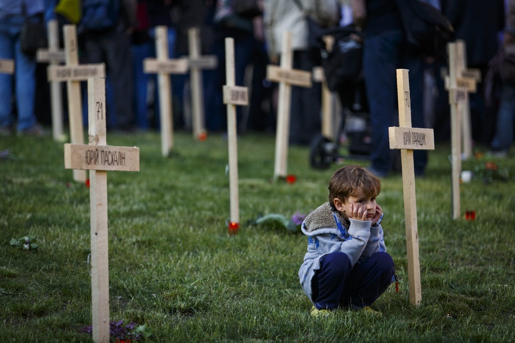 In Prague, the Czech Republic, a young boy sat quietly in a symbolic cemetery for those lost in Ukraine's protests.
