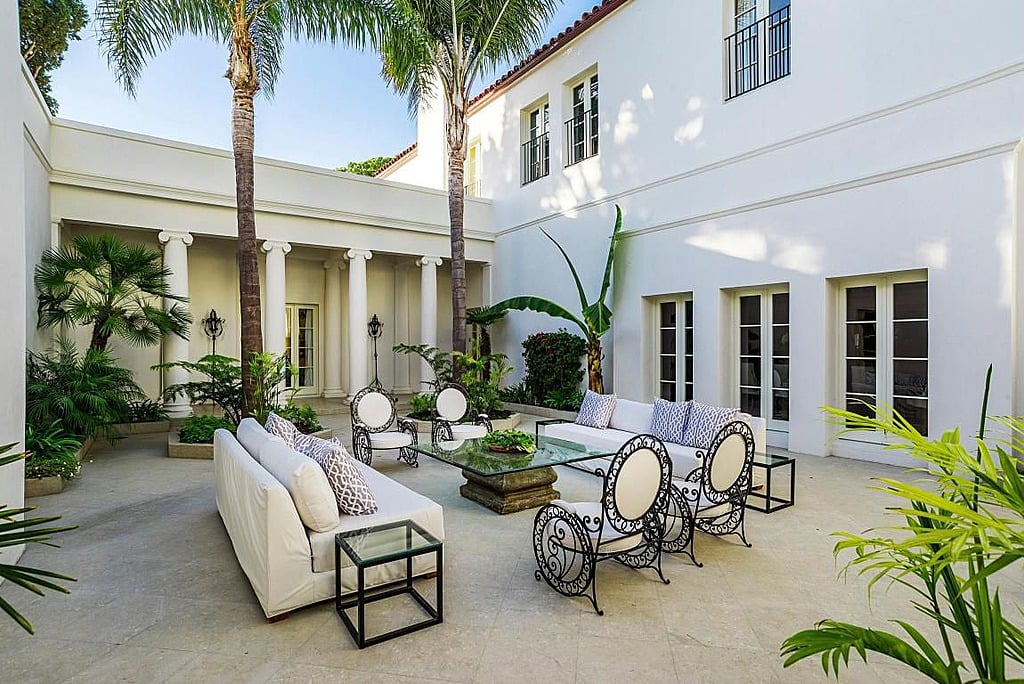 The columns and palm trees in this outdoor sitting area make it feel more like a luxurious resort than a private residence.