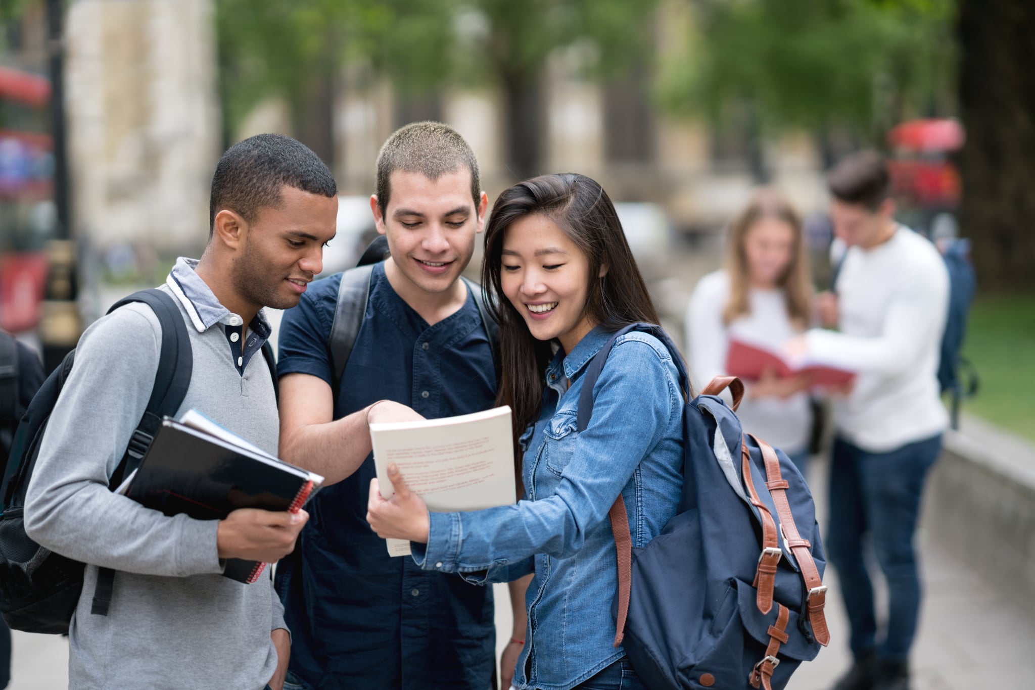 Portrait of a happy multi-ethnic group of students studying outdoors and smiling - education concepts