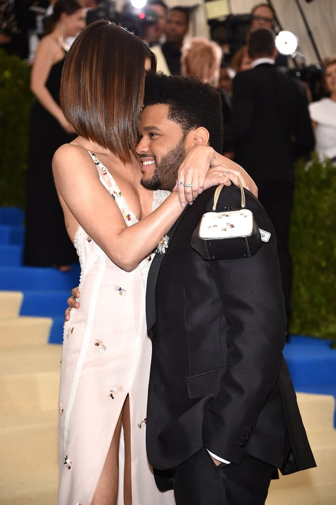 Selena Gomez and the Weeknd are getting more and more comfortable with showing off their love for the cameras. Shortly after making their relationship Instagram official at Coachella, the couple made their red carpet debut at the Met Gala in NYC on Monday. While the Weeknd looked dapper in a tux and tie, the 13 Reasons Why executive producer looked beautiful in a flowing white Coach gown and purple eyeshadow. Aside from posing for the flashing cameras, the two also snuck in a little PDA as they pulled each other in close for a hug. They looked right out of a wedding magazine!