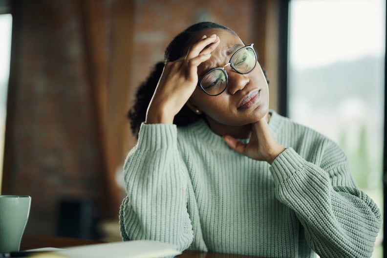 Woman touching pressure points on her head and neck to help relieve a tension headache.