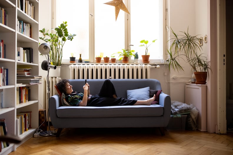 Nonbinary person texting on the couch