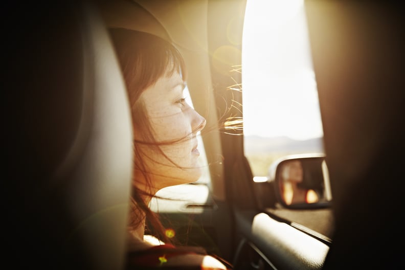 Woman with hair blowing looking out window of car at desert landscape