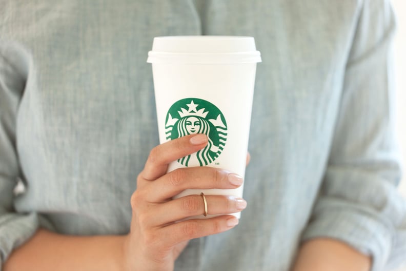 Person holding a Starbucks drink cup; find out which Starbucks drinks are low-calorie.