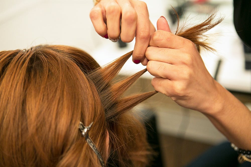 Starting with a section of hair from behind one ear, separate it into three strands.