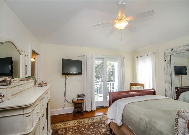 The cozy master bedroom has a private balcony and a wall-mounted TV.