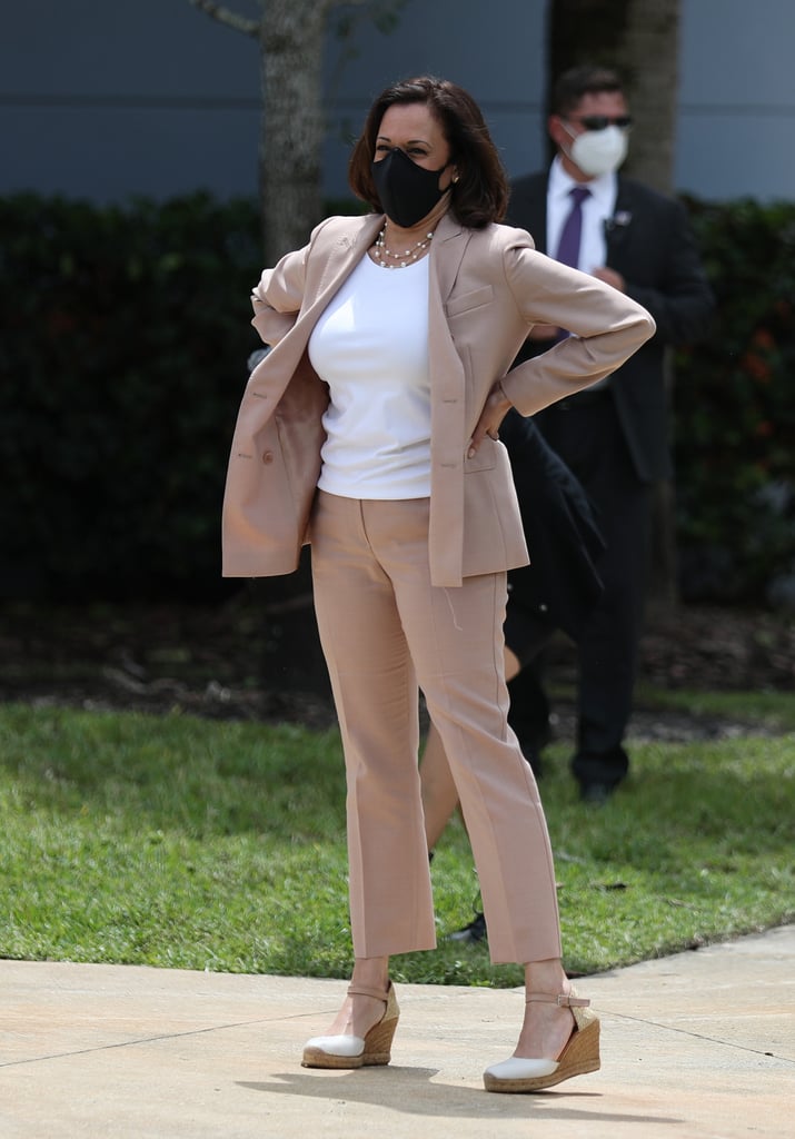 Kamala's September 2020 Miami campaign stop called for a fitted camel suit, the blazer worn undone, with her chainlink pearls, espadrille wedges, and a protective face mask.