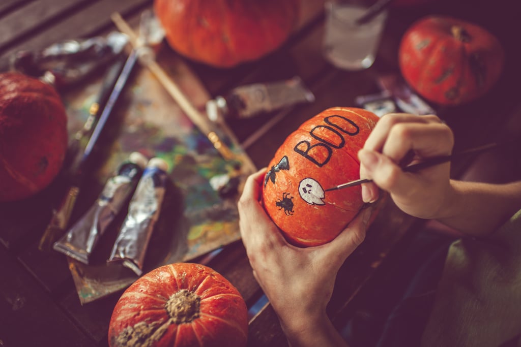 Kvinna som målar på pumpa och förbereder sig för Halloween på hösten