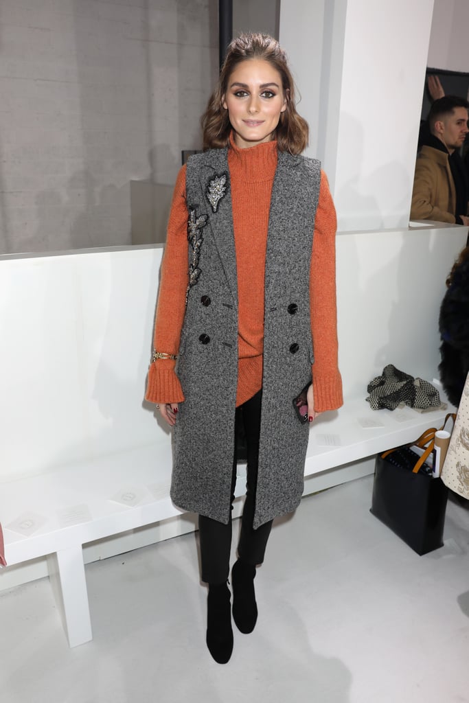 Olivia wore an orange sweater and a long vest coat at the Emilia Wickstead show.