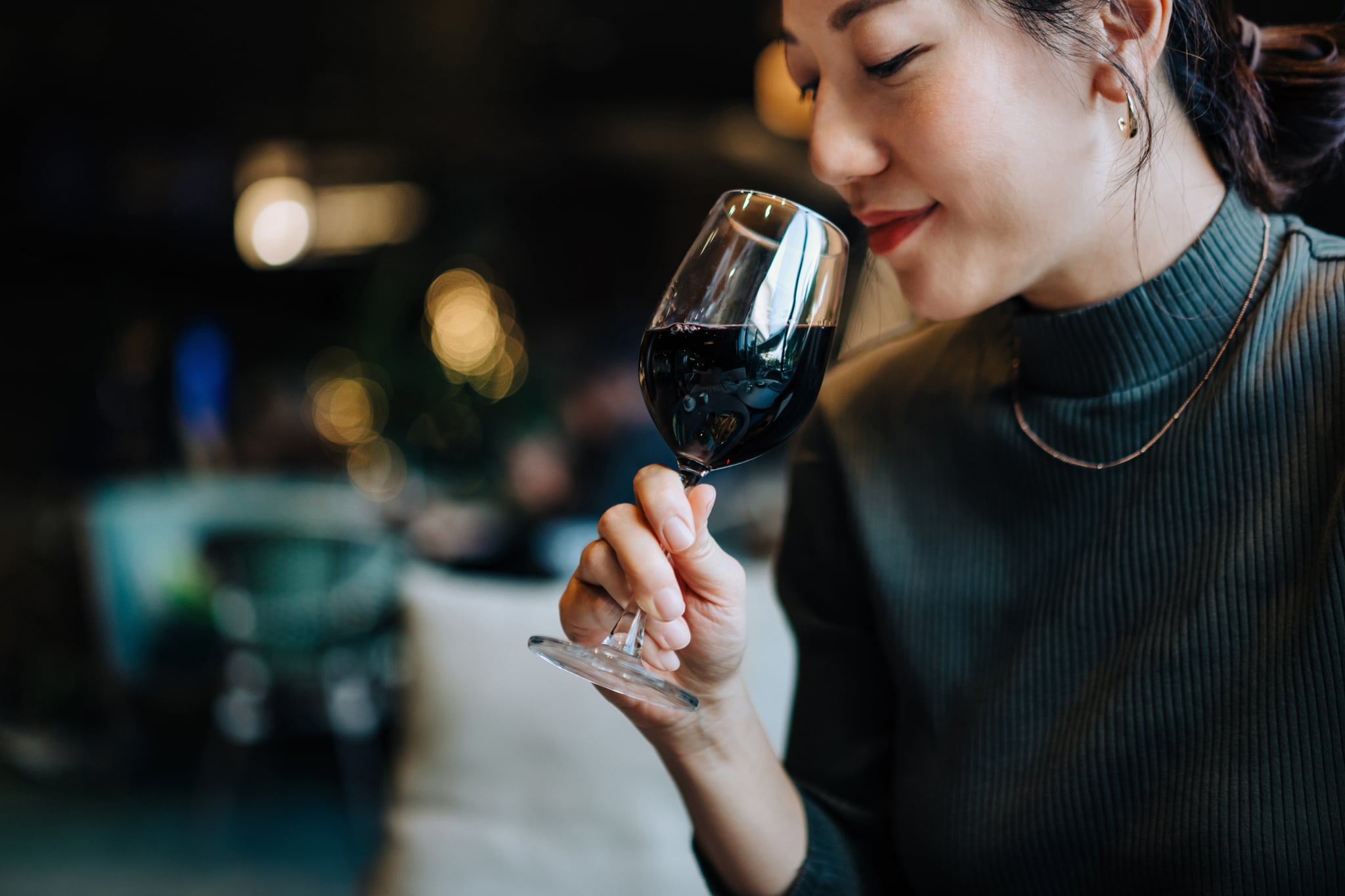 Woman drinking glass of red wine in restaurant. 