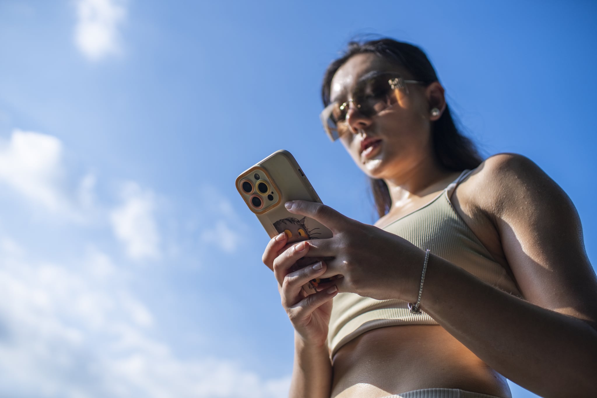 Woman standing outside in workout clothes while looking at phone.