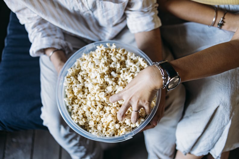 A from above view of an anonymous Asian woman and her Indian boyfriend eating snacks while spending their leisure time together.