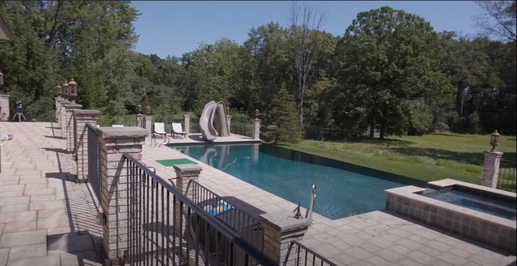 The kitchen opens up straight to the back patio where there's not only a pool with a slide but a grill, a hot tub, a TV, and a gorgeous lawn. Talk about an ideal summer setup.