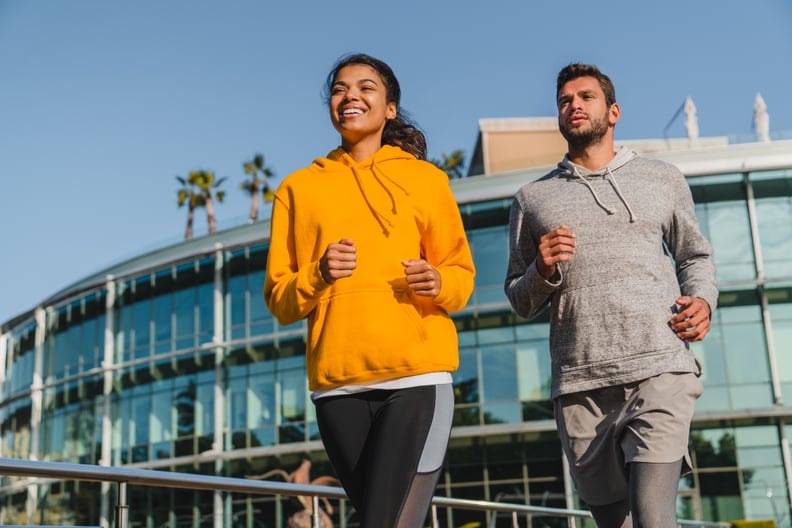Happy young mixed race couple jogging in sporty outfit in urban area