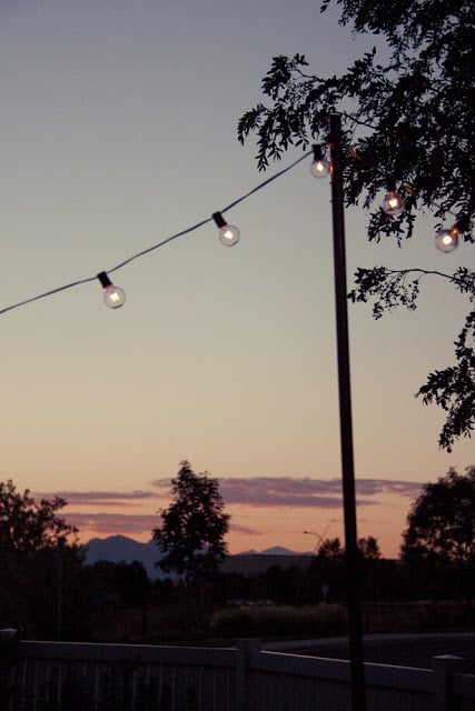 This project was so rewarding. The lights cast a warm, flattering glow that will be perfect for entertaining. I also love that we can take them down easily by lifting the poles out of the ground and unhooking the lights. Easy! 
You should do it. 
Here's the cost breakdown: 
Three 10-foot-long pieces of electrical conduit, 3/4 inch in diameter: $3.98 each — $11.94
One 10-foot-long piece of plastic piping (it was in the same aisle as the conduit, so I'm assuming it also has an electrical function) — $2.92
Two packages of single anchor pipe straps, 3/4 inch diameter — 98 cents each — $1.96
One package of 1/2-inch "Knock Out Seals" — $1.30
Two cans of Rust-Oleum Hammered Dark Bronze Spray Paint — $5.98 each for a total of $11.96
Total: $30.08! 
The string lights are from Target and cost $12.95 for each 20-foot strand. Our deck is 10 by 20 feet, so we needed two strands. 
This brings the final total for this project to $55.98! Not bad considering the many more expensive alternatives out there. I'm in love.