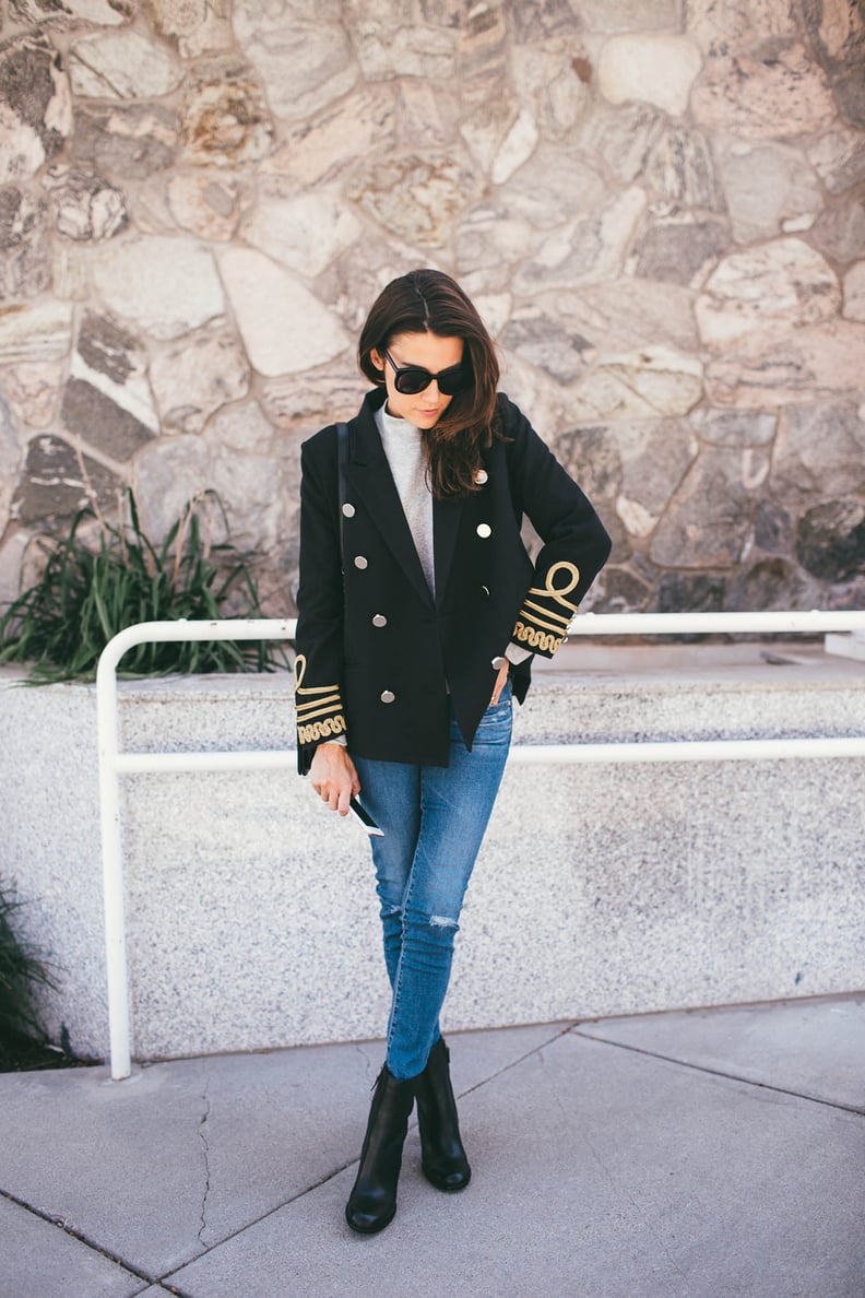 A double-breasted blazer layered over a mock neck sweater, jeans, and ankle boots.