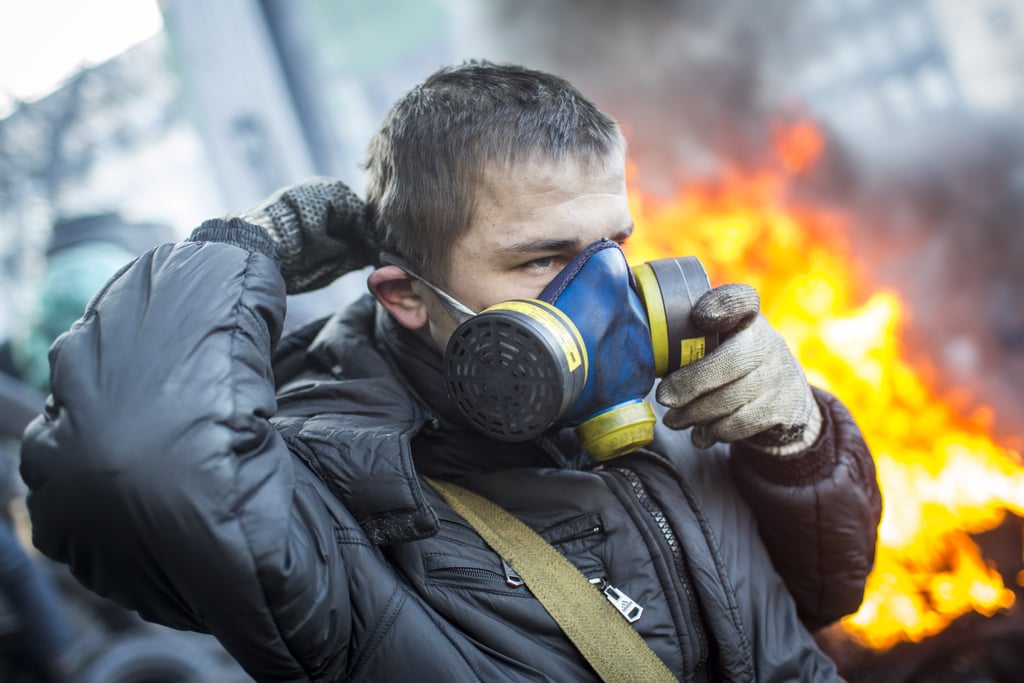 A protester put on his gas mask near the burning piles.