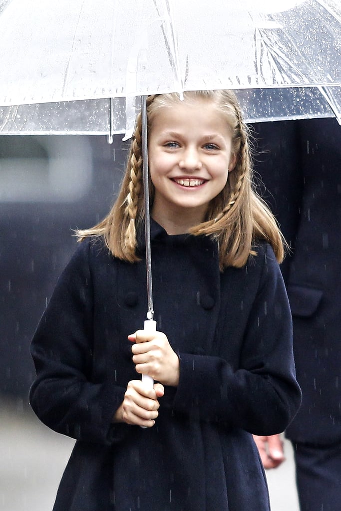 Princess Leonor smiles under an umbrella on Spain's National Day.