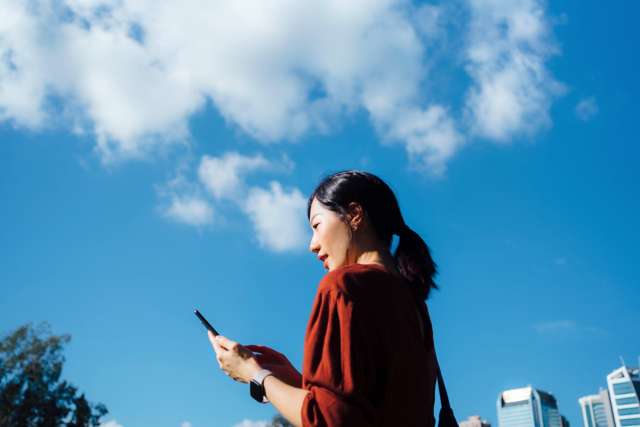 woman looking at her phone backdropped by a blue sky
