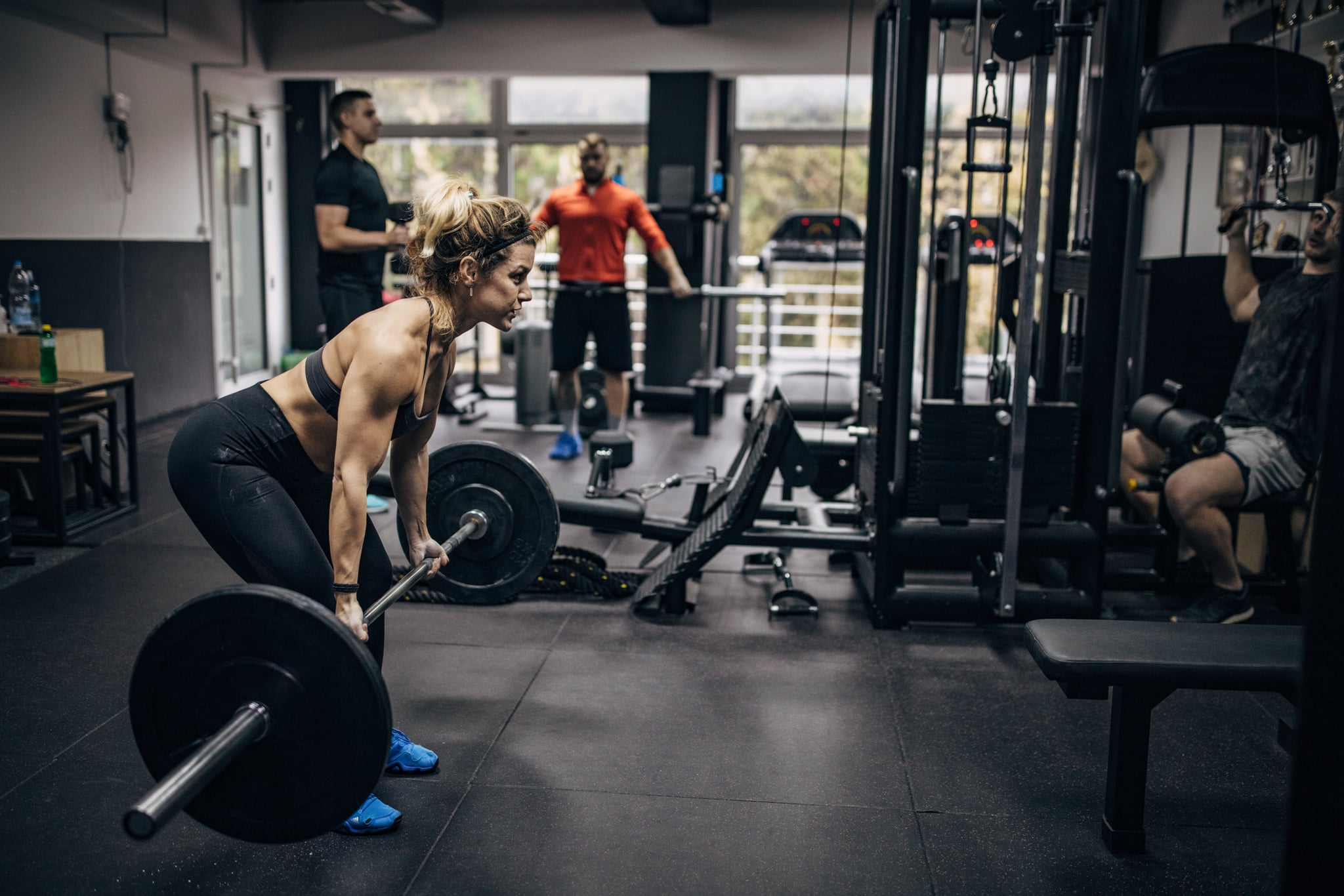Group of people, strong woman exercising with weights in gym.