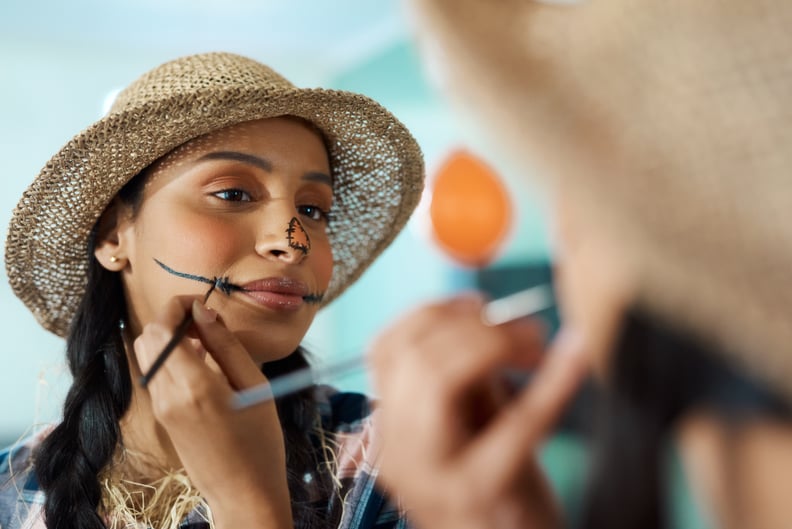 woman painting her face for a scarecrow Halloween costume using DIY face paint