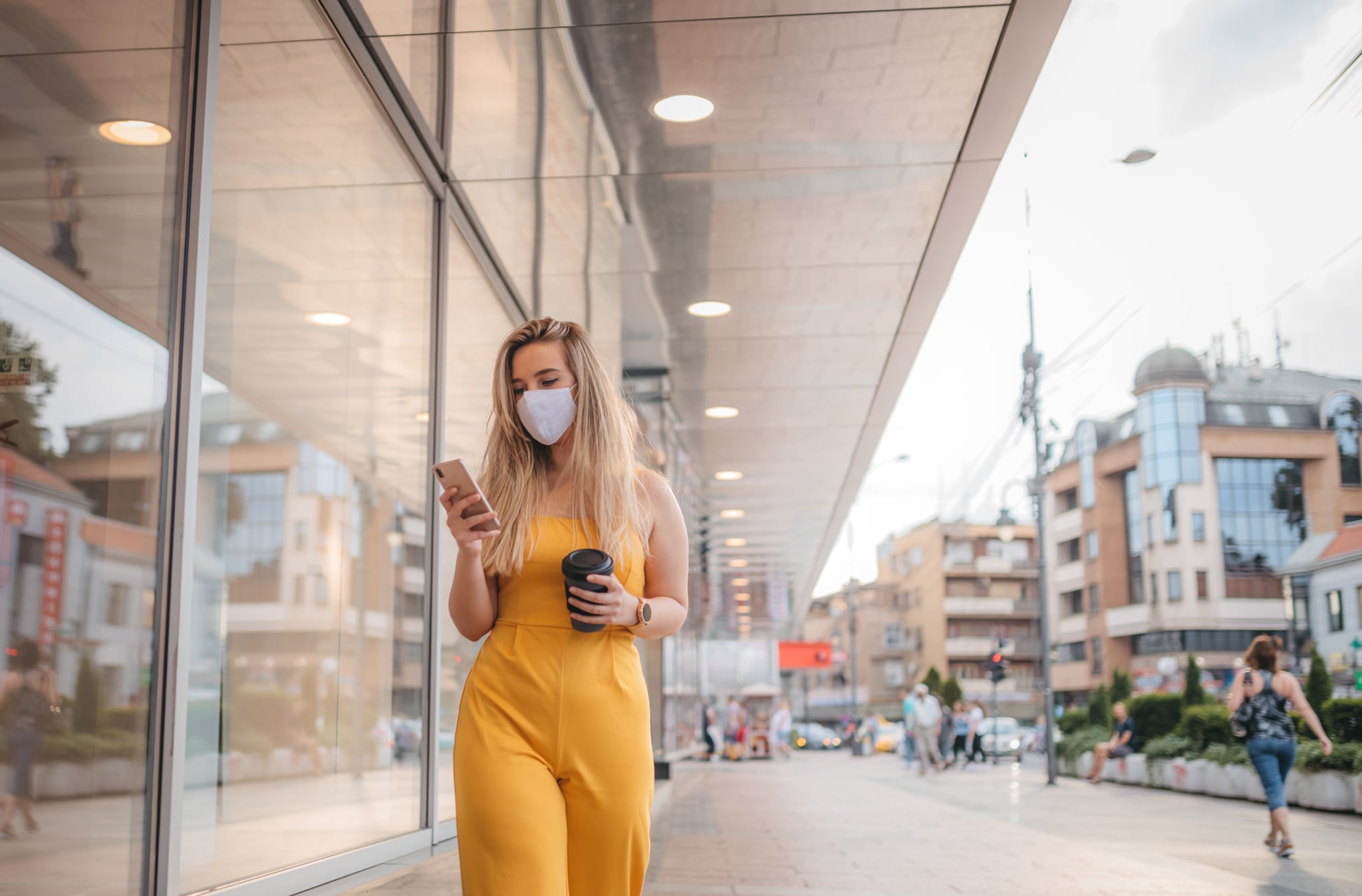 Woman wearing protective mask, using mobile phone