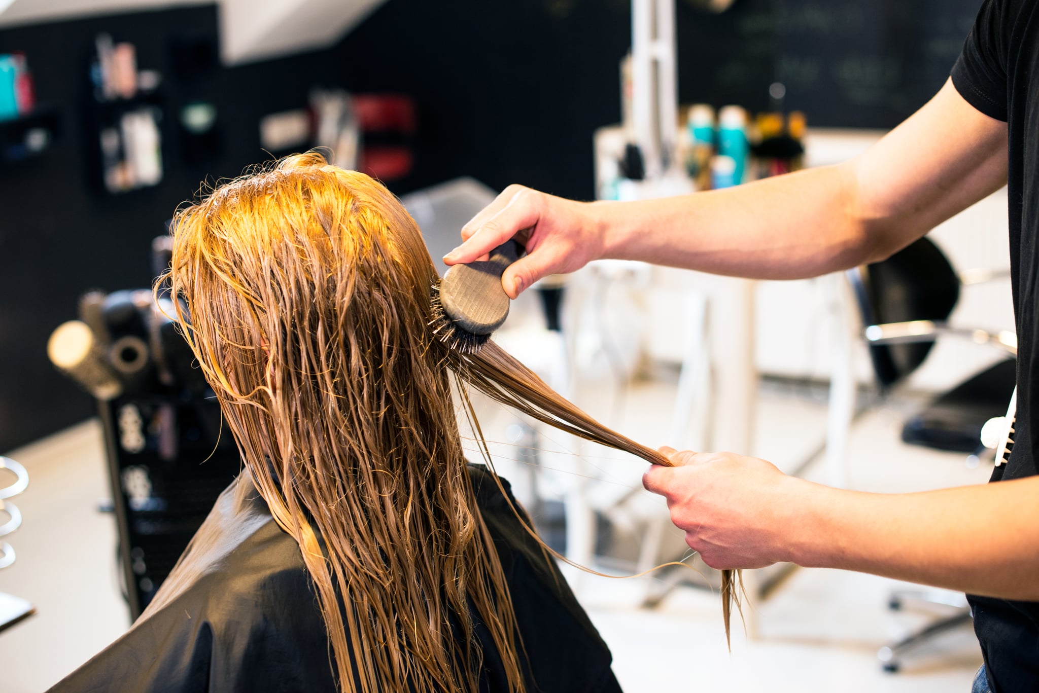 Hairdresser is brushing hair of young woman