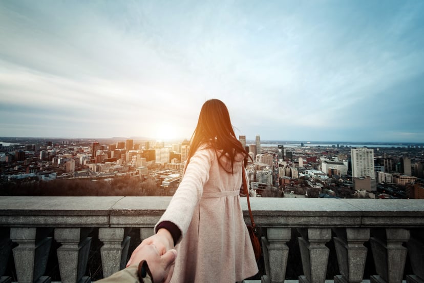 Happy traveller couple holding hands enjoying the spectacular city skyline of Montreal from view point