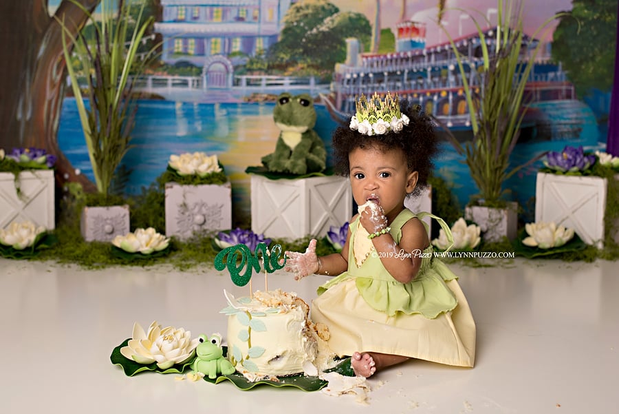 How's that line go again? "If you do your best each and every day, good things are sure to come your way?" That's what we thought, and this gorgeous Princess and the Frog-themed cake smash channels the sweet message from the beloved Disney flick. Photographer Lynn Puzzo of Fayetteville, GA, was recently asked to stage a Tiana-inspired photo shoot starring Zoie, who will celebrate her first birthday on Nov. 3. Naturally, she went above and beyond to get every little detail just right.
"Zoe's mom, Brandis, chose Princess and the Frog as her theme for her baby girl's session," Lynn told POPSUGAR over email. "Although I am a huge Disney fan, I had not yet seen the movie, so I anxiously waited for it to come on TV to learn all about Tiana! I immediately fell in love with Tiana's character. She is so motivated and driven." 
Determined to make the pictures really pop, Lynn got to work gathering all the props she needed — including a stuffed frog. "I wanted to create the set to have a bayou feel to it," explained Lynn. "I used moss, lily pads, water lilies, and some other greenery to complement the beautiful Tiana-inspired backdrop, which I purchased for the session. And, of course, the adorable frog was an absolute necessity!"
And this isn't the first Disney-themed session she's done. Lynn previously shot a full-blown Aladdin cake smash that even Jafar would smirk at! Read on to get a peek at these sweet photos, which would certainly get a princess's stamp of approval. 

    Related:

            
            
                                    
                            

            This Little Girl Had a Starbucks Cake Smash, and We See Frappuccinos in Her Future!
