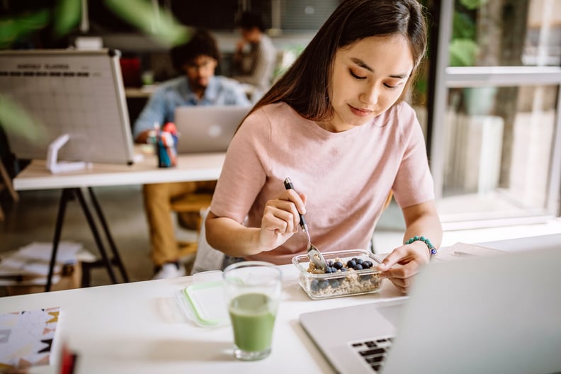 Young Asian blogger having vegetarian breakfast at work