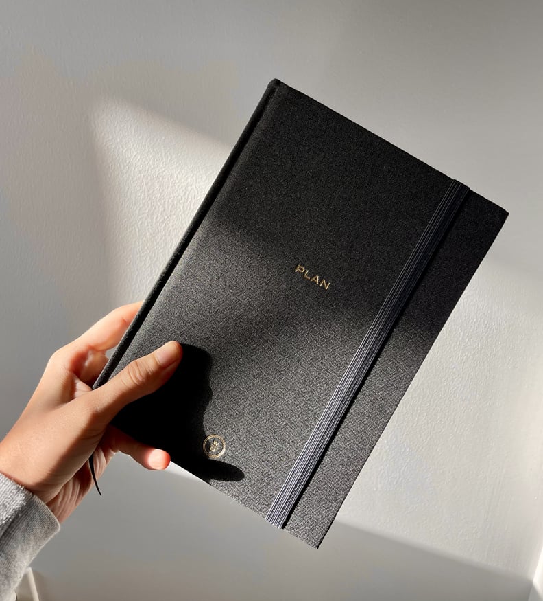 Person holding the Wit & Delight black linen weekly and monthly planner.